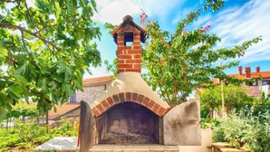 A brick-built outdoor oven with a chimney, surrounded by greenery and a stone wall. - Apartment 1352/12722 (Istria - Pula), 750m from the beach (Pula)
