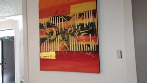 A large abstract painting with a signature on a white wall in a hallway. - Resortstay in American village (Chatan)