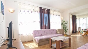 A living room with a sofa, a coffee table, a TV on a stand, and a dining area with chairs and a table. - Apartment 1359/16593 (Istria - Peroj), 500m from the beach (Peroj)