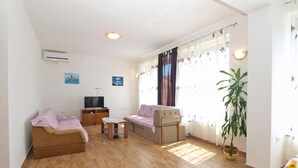 A living room with a sofa, a television, a small table, and a potted plant. - Apartment 1359/16593 (Istria - Peroj), 500m from the beach (Peroj)