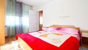 Une chambre à coucher comprenant un lit, une table de chevet, une armoire et une fenêtre avec des rideaux.