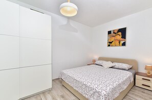 Un dormitorio con cama, mesitas de noche, armario y lámpara en el techo.