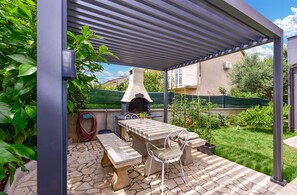 An outdoor patio with a stone table, a bench, a grill, and a pergola structure. - Apartment 1363/12837 (Istria - Valbandon), 500m from the beach (Valbandon)