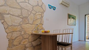 A dining area with a stone wall, wooden table, and chairs. - Studio apartment 1364/12839 (Istria - Pula), 2500m from the beach (Pula)