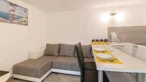 A modern, compact room with a sofa, dining table set for two, and a small kitchen area. - Apartment 1365/12840 (Istria - Pula), 1500m from the beach (Pula)