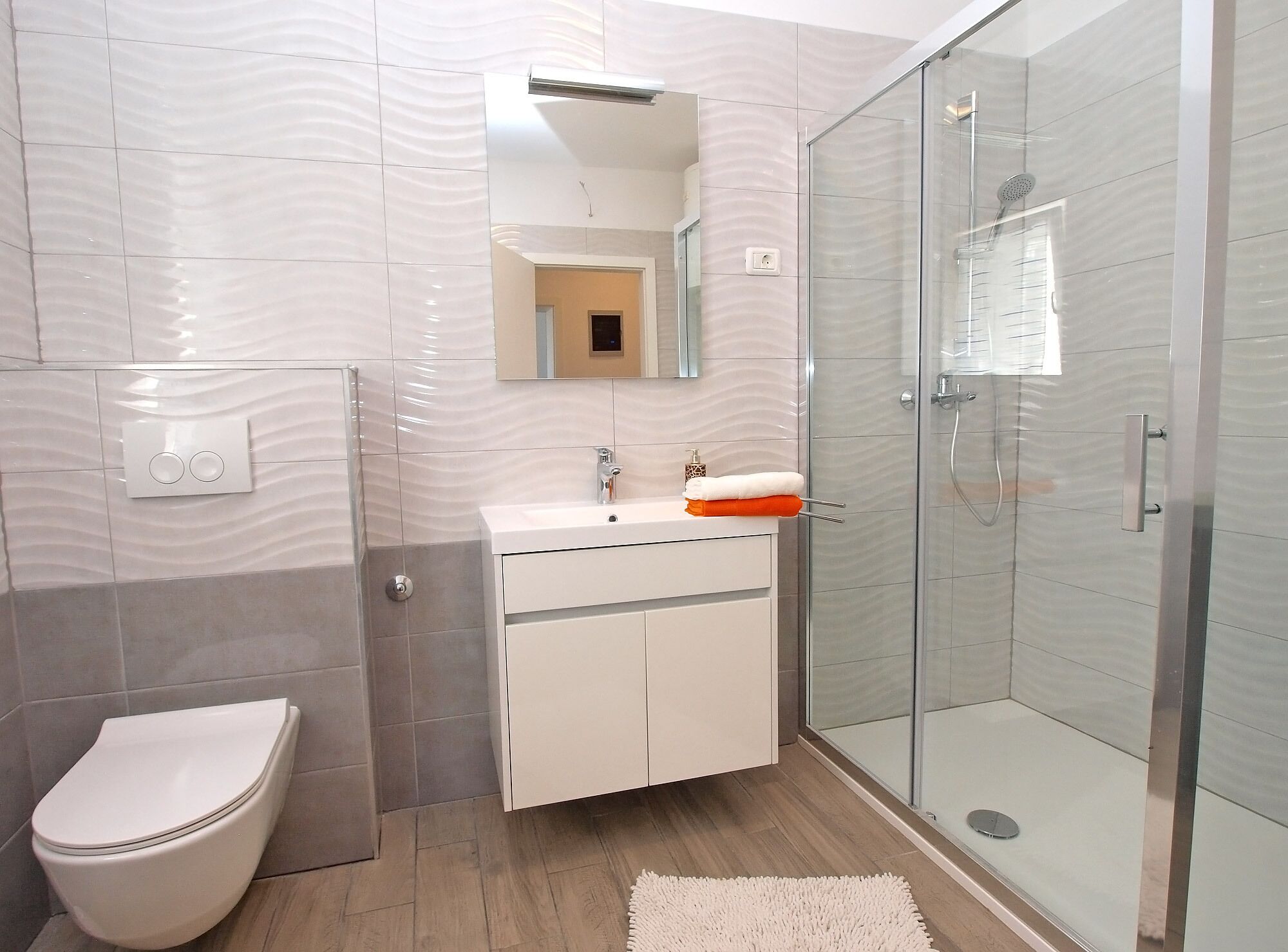A modern bathroom with a toilet, sink, and glass shower enclosure.