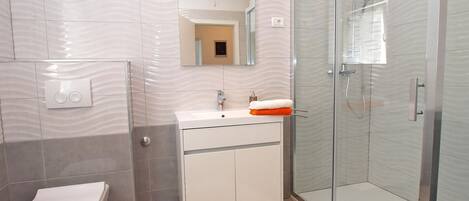 A modern bathroom with a toilet, sink, and glass shower enclosure.