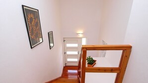 Un escalier en bois avec une rampe, des murs blancs et une porte en haut.