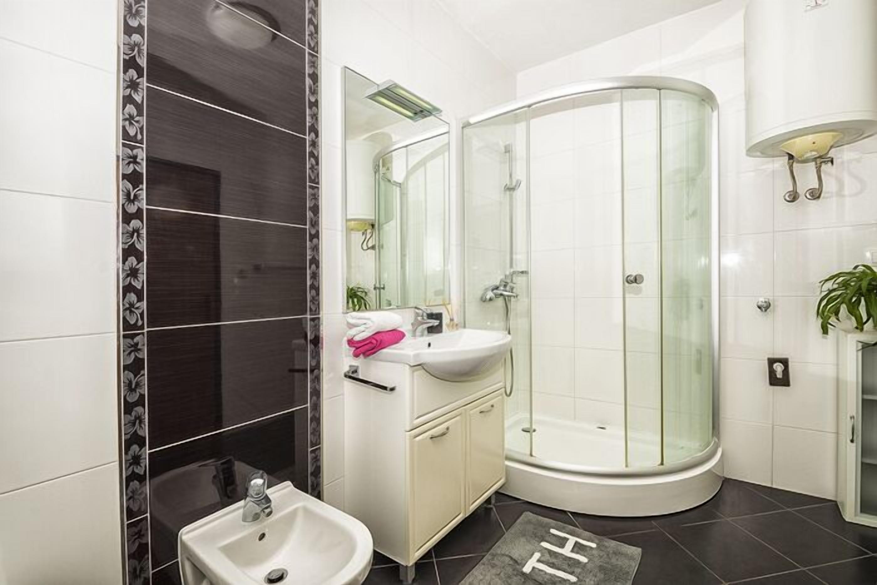 Een moderne badkamer met een glazen douchecabine, een wit wastafelmeubel en een spiegel.