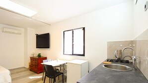 A compact kitchen with a sink, stove, and a small refrigerator. There is a dining table with a chair and a TV mounted on the wall. - Apartment 1371/12911 (Istria - Pjescana Uvala), 100m from the beach (Pjescana Uvala)