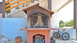 A brick-built outdoor fireplace with a chimney, surrounded by a blue wall and a staircase. - Apartment 1374/12936 (Istria - Pula), 2500m from the beach (Pula)