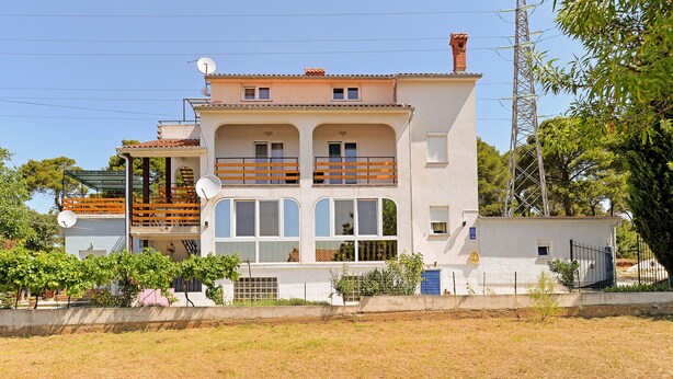 A two-story building with a balcony on the upper floor, a satellite dish on the roof, and a power line tower in the background. - Apartment 1374/12936 (Istria - Pula), 2500m from the beach (Pula)