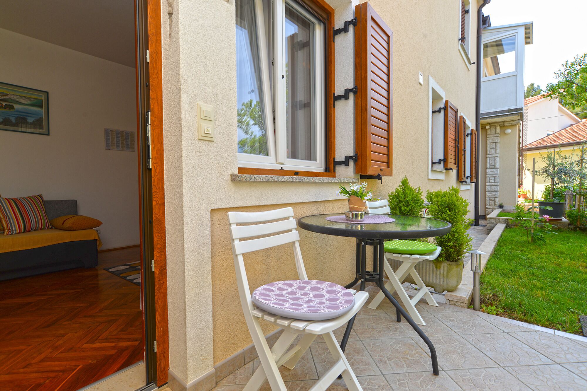 Un patio con una mesa y sillas, un pequeño jardín y vistas a la calle.
