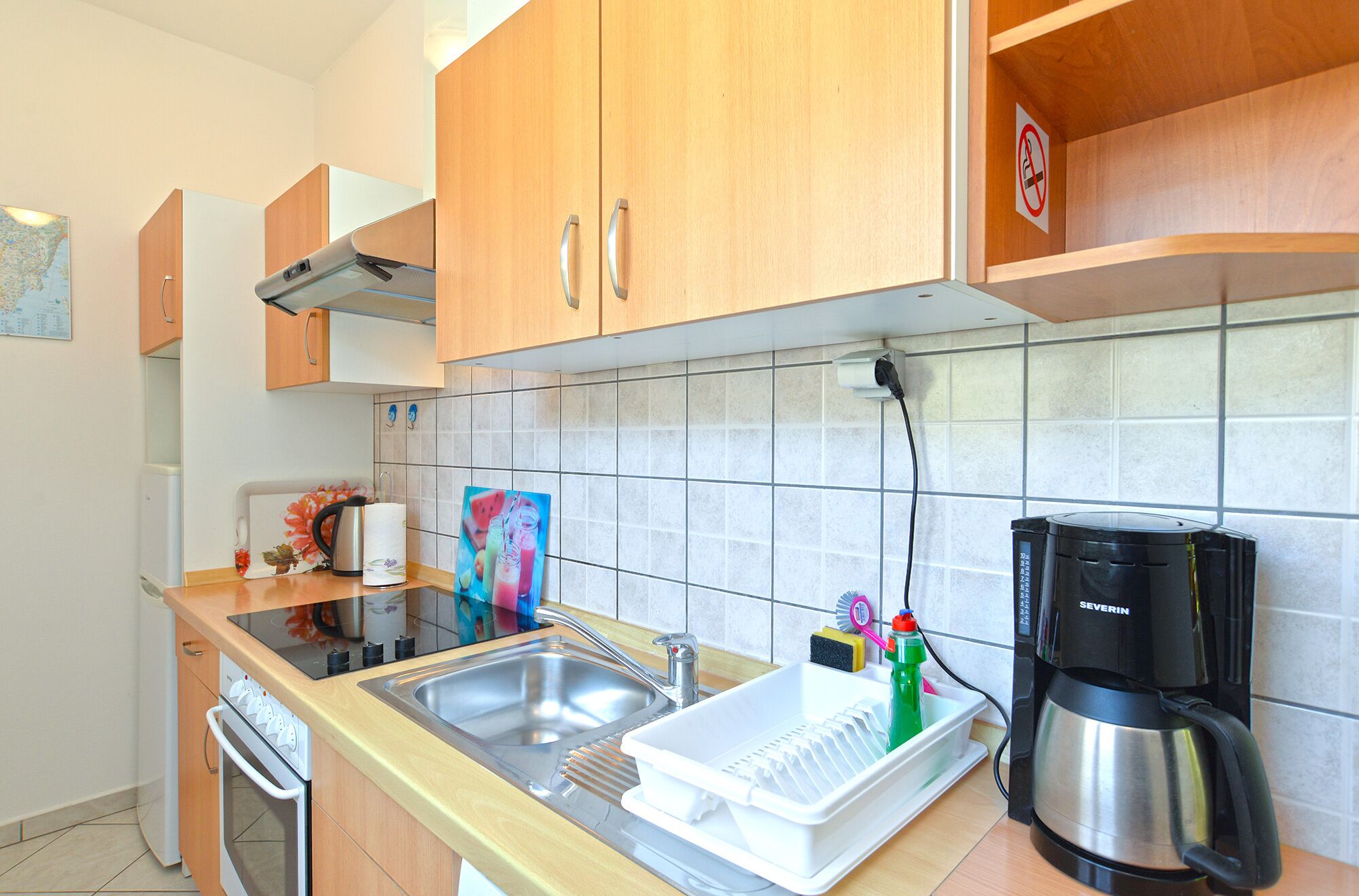 A modern kitchen with wooden cabinets, a stainless steel sink, a coffee maker, and a dish drying rack.