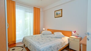 A bedroom with a bed, nightstand, and a painting on the wall. - Apartment 1377/13012 (Istria - Poreč), 800m from the beach (Poreč)