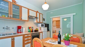 A compact kitchen with wooden cabinets, a microwave, a coffee maker, and a dining table with chairs. - Apartment 1377/13012 (Istria - Poreč), 800m from the beach (Poreč)