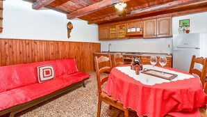 A cozy room with a red sofa, wooden dining table, and kitchen area with wooden cabinets. - House 1378/12993 (Istria - Galižana), 7500m from the beach (Galižana)