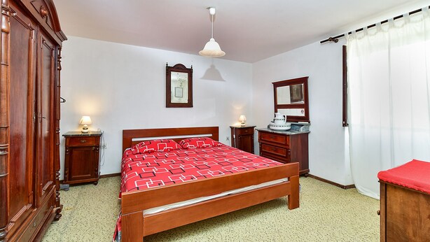A bedroom with a wooden bed, two bedside tables with lamps, a mirror, and a window with curtains. - House 1378/12993 (Istria - Galižana), 7500m from the beach (Galižana)