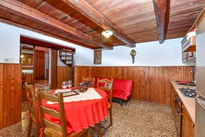 A dining area with a wooden table and chairs, a kitchen with a stove, and a wooden ceiling. - House 1378/12993 (Istria - Galižana), 7500m from the beach (Galižana)