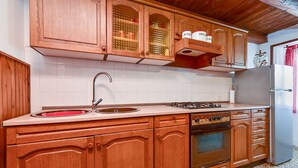 A kitchen with wooden cabinets, a stainless steel sink, a gas stove, and a built-in oven. - House 1378/12993 (Istria - Galižana), 7500m from the beach (Galižana)