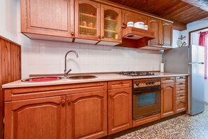 Una cucina con mobili in legno, un lavello in acciaio inox, un piano cottura a gas e un forno integrato.