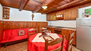 A cozy kitchen with wooden cabinets, a dining table set for four, and a red tablecloth. - House 1378/12993 (Istria - Galižana), 7500m from the beach (Galižana)