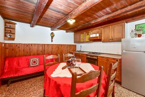 Una cucina accogliente con mobili in legno, un tavolo da pranzo per quattro persone e una tovaglia rossa.