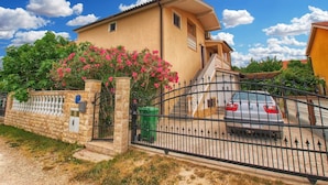 A two-story house with a stone wall and a metal gate.