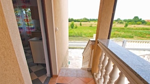 A balcony with a view of a green field and a white railing.