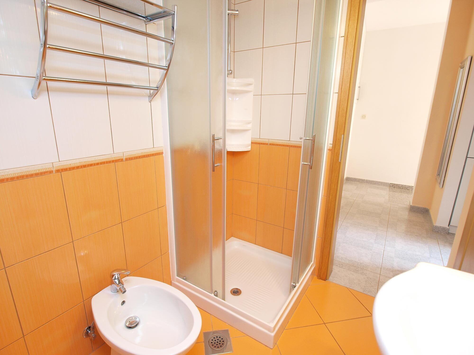 A bathroom with a glass-enclosed shower, a sink, and a toilet.