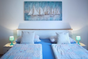 Ein Schlafzimmer mit einem Bett, zwei Nachttischen und einem Bild von Segelbooten.