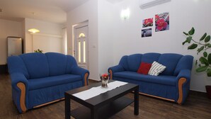 A living room with two blue sofas, a wooden coffee table, and a potted plant.