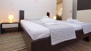 A double bed with white linens and patterned blankets, a bedside table with a lamp, and a striped rug.