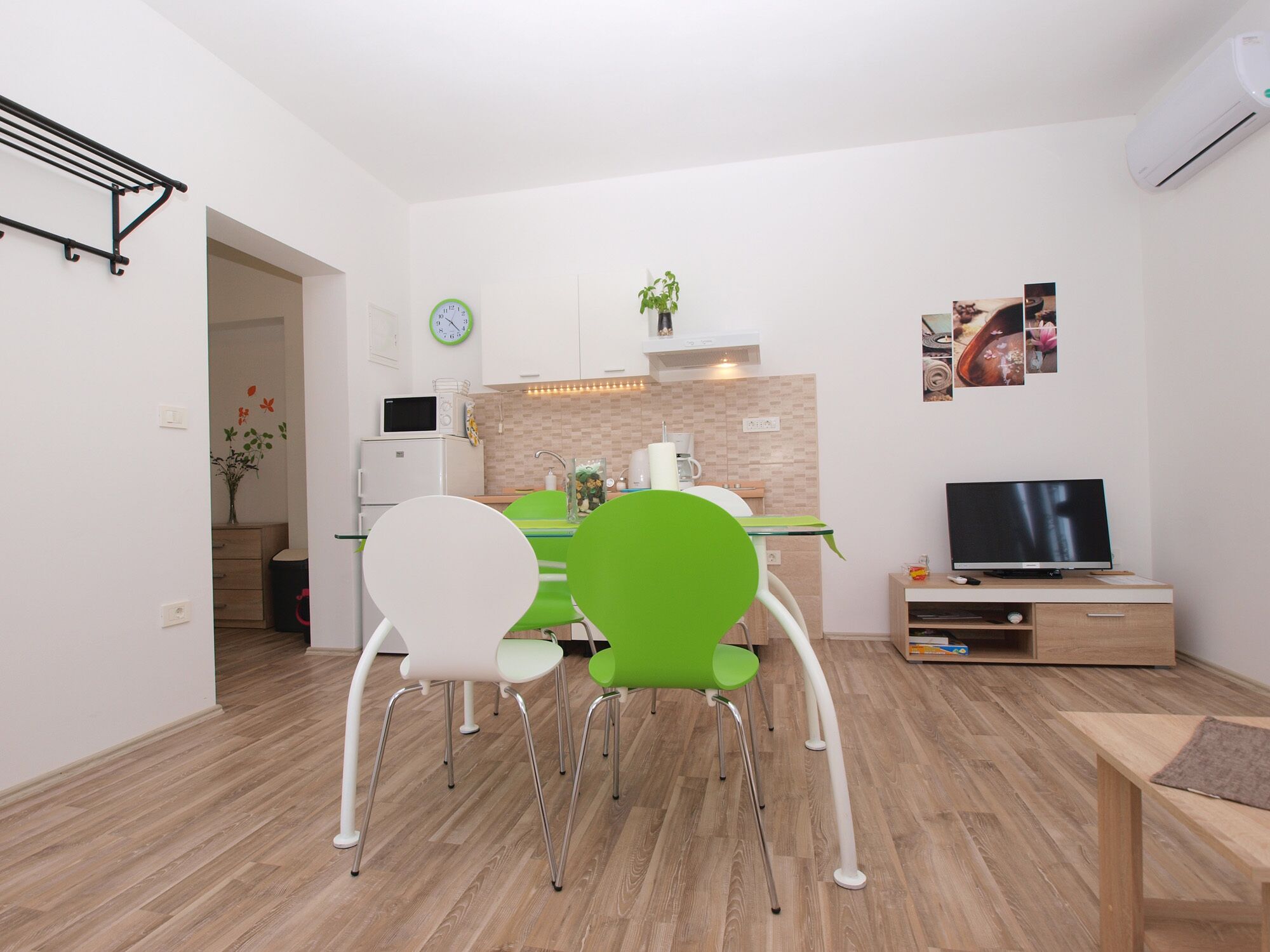 Un espacio habitable compacto con comedor, kitchenette y televisor.