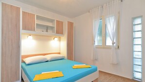 A bedroom with a bed, a nightstand, a window with curtains, and built-in shelving above the bed. - Apartment 1405/13211 (Istria - Peroj), 30m from the beach (Peroj)