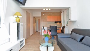 A modern living room with a grey sofa, a glass coffee table with a vase of flowers, and a white cabinet. - Apartment 1405/13211 (Istria - Peroj), 30m from the beach (Peroj)