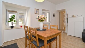 A dining area with a wooden table, four chairs, a vase with flowers, and a ceiling light.