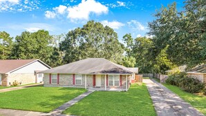 A two-story house with a brick facade, a front porch, and a well-maintained lawn.