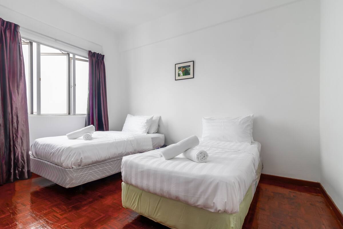 Ein Hotelzimmer mit zwei Betten, einem Vorhangfenster und einem kleinen gerahmten Bild an der Wand.