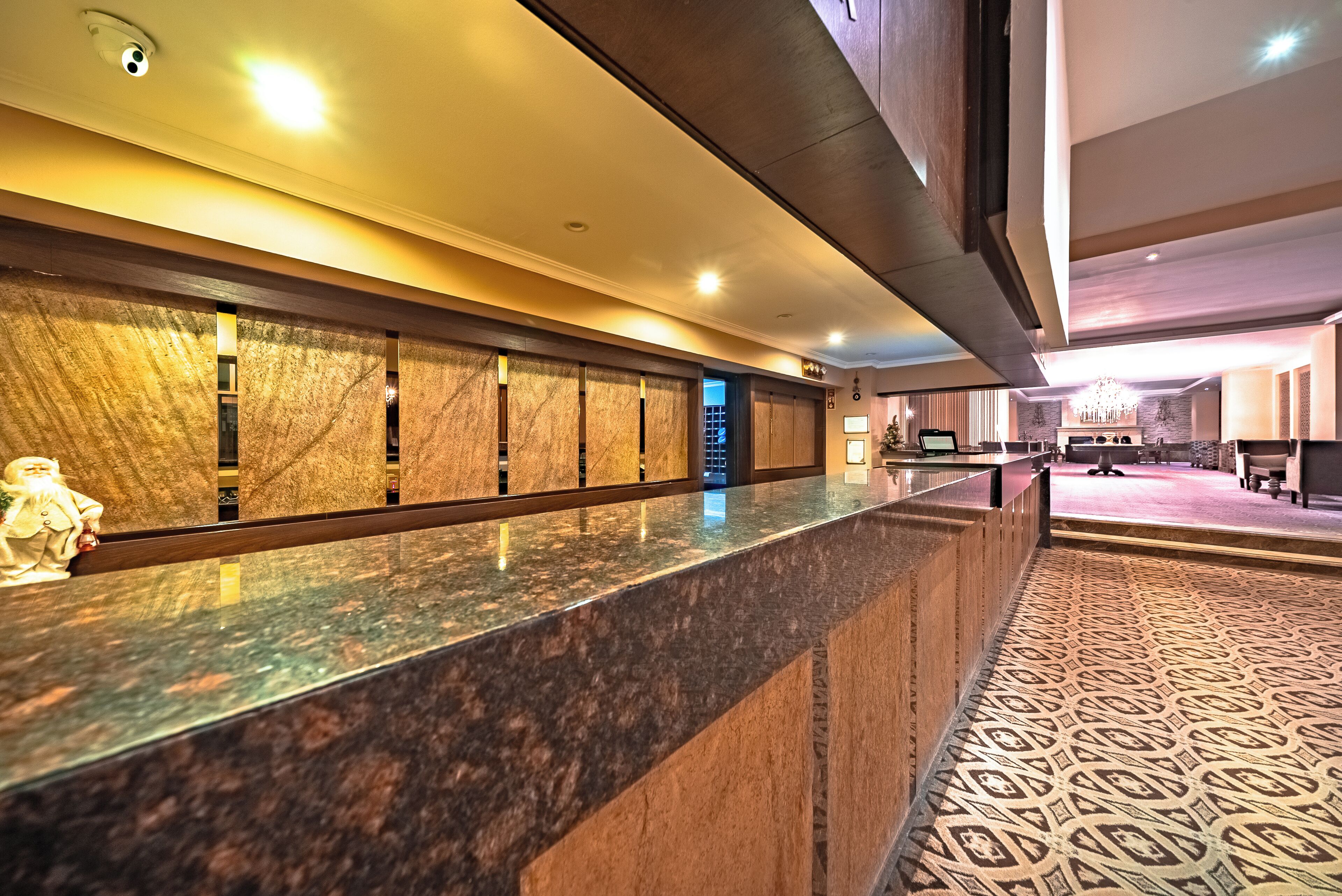 A hotel reception area with a marble counter, a statue, and a patterned carpet.