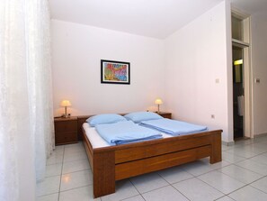Una camera da letto con un letto in legno, due comodini con lampade, un quadro appeso al muro e una porta che dà su un'altra stanza.