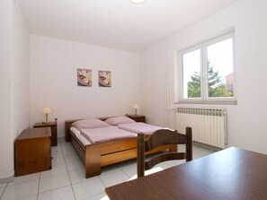 Um quarto com cama, mesas de cabeceira, uma janela e um radiador.