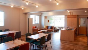 A modern dining area with tables and chairs, a kitchen island with a sink, and a seating area with sofas and chairs. - The Stay Wakkanai- Hostel (Wakkanai)