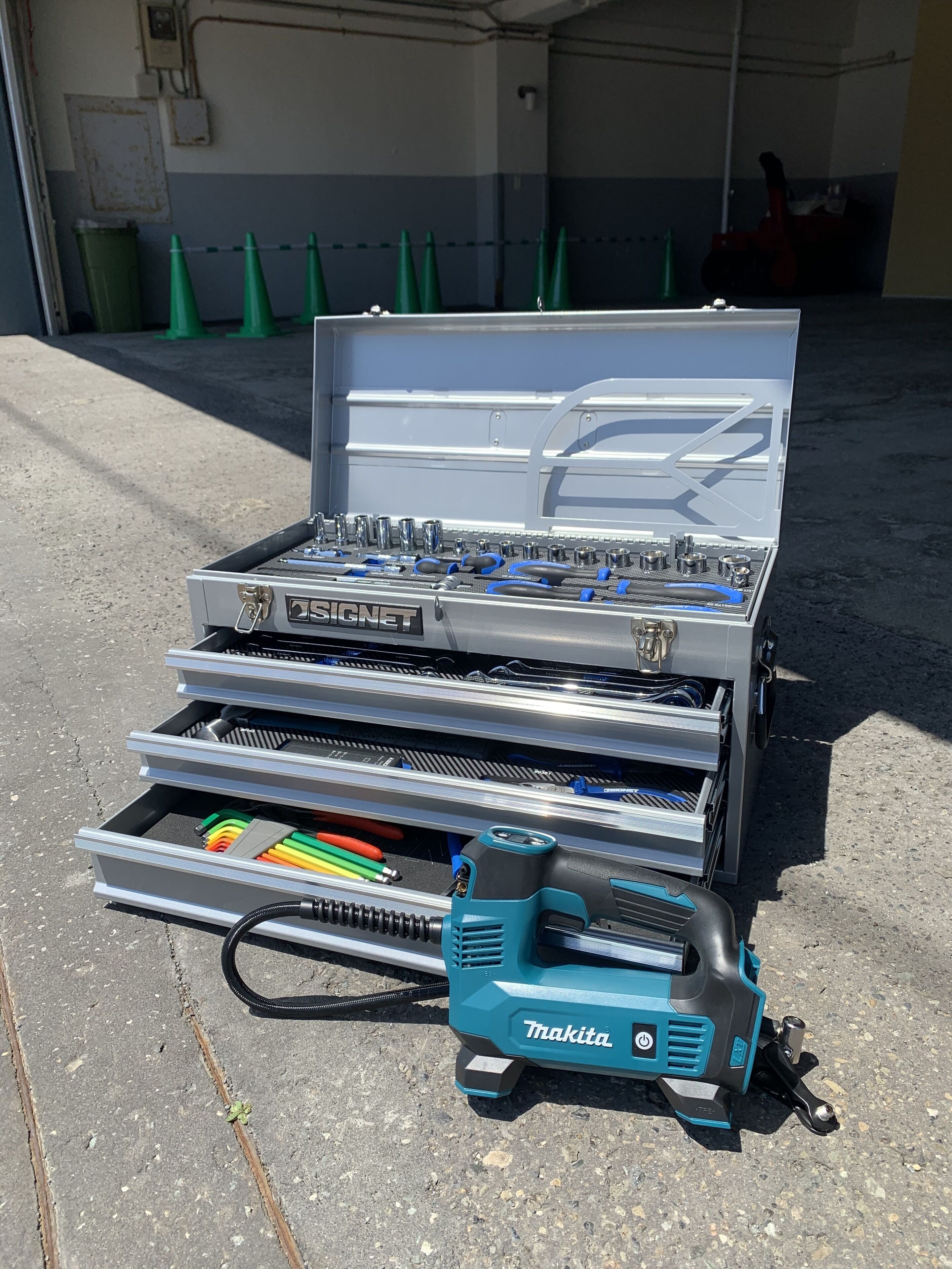 A toolbox with a power tool on a concrete surface.