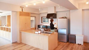 A modern kitchen with a central island, stainless steel appliances, and wooden cabinetry. - The Stay Wakkanai- Hostel (Wakkanai)