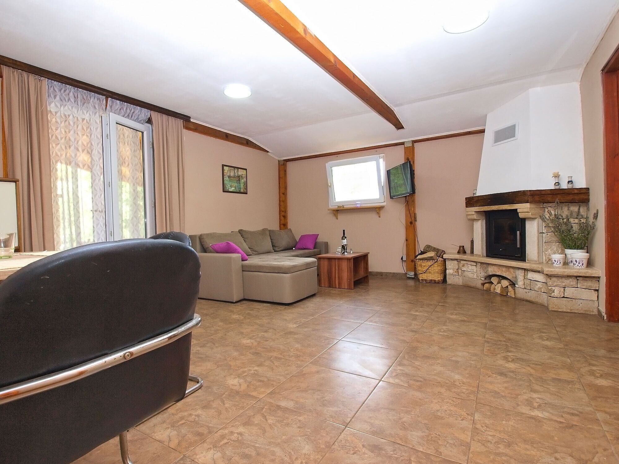 A living room with a sofa, a television, a fireplace, and a window.