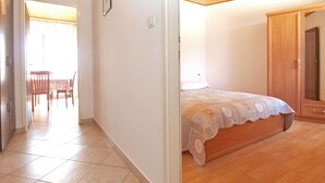 Un dormitorio con cama, armario de madera y una puerta que da a otra habitación.