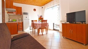 Un espacio habitable compacto con kitchenette, comedor y televisor.