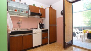 A kitchen with wooden cabinets, a stove, an oven, and a coffee machine. - Apartment 1453/13446 (Istria - Banjole), 100m from the beach (Banjole)