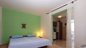 A bedroom with a bed, a nightstand, a wall-mounted lamp, and a view into the kitchen. - Apartment 1453/13446 (Istria - Banjole), 100m from the beach (Banjole)